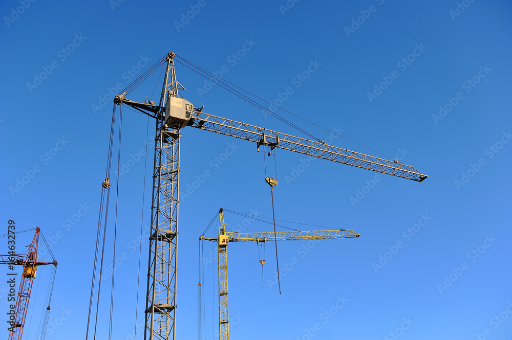 Construction cranes against the blue sky