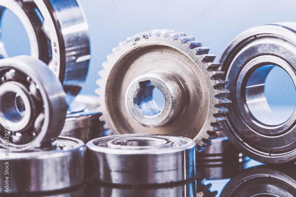 Group of various ball bearings and gears close up on nice blue background with reflections. Toned Group of various ball bearings and gears close up on nice blue background with reflections. Toned