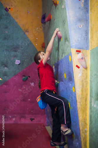 girl rock climber working on the problem bouldering in climbing shoes