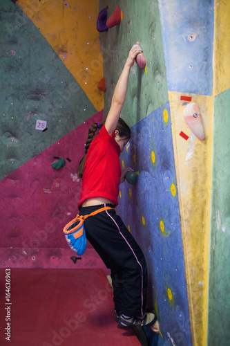 girl rock climber working on the problem bouldering in climbing shoes