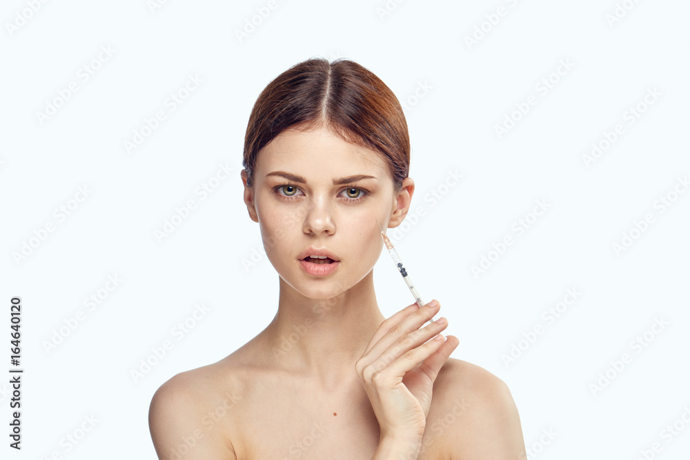 Young beautiful woman on white isolated background holds a syringe, plastic surgery, medicine Young beautiful woman on white isolated background holds a syringe, plastic surgery, medicine