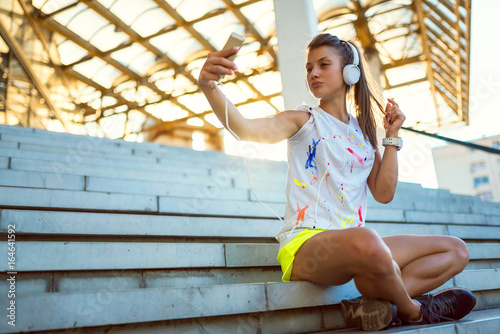 Urban sport girl with earphones  taking selfie