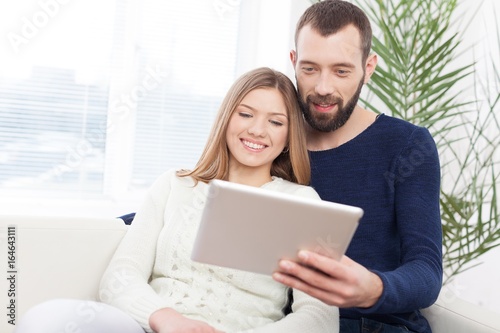 Cheerful young couple working on digital tablet.