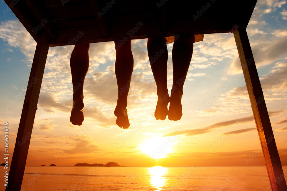 Φωτογραφία happiness concept, silhouette of feet of couple sitting on the pier at sunset be