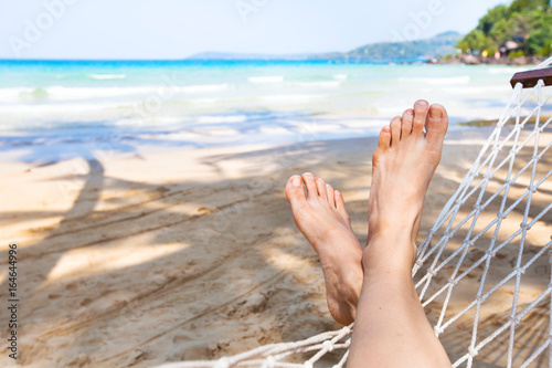 beach holidays background, vacation and relaxation concept, feet of person in hammock