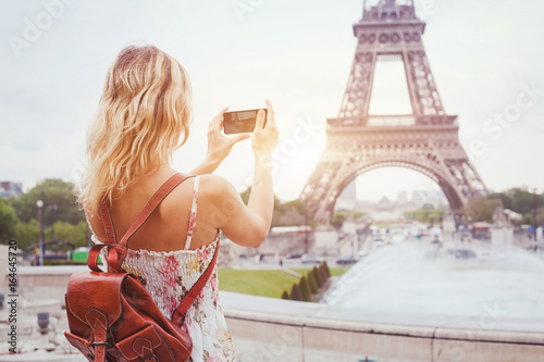 tourist in Paris visiting landmark Eiffel tower, sightseeing in France, woman taking photo on mobile phone