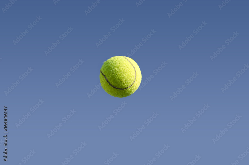 Closeup of tennis ball in mid air isolated on blue sky 