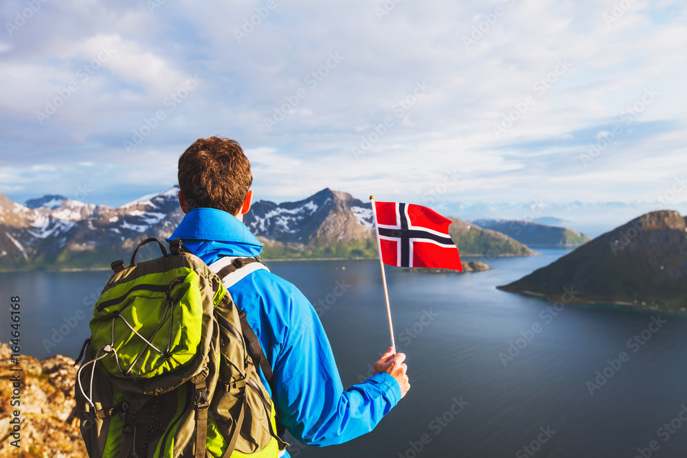 Φωτογραφία travel to Norway, hiker traveler with backpack holding norwegian flag and lookin