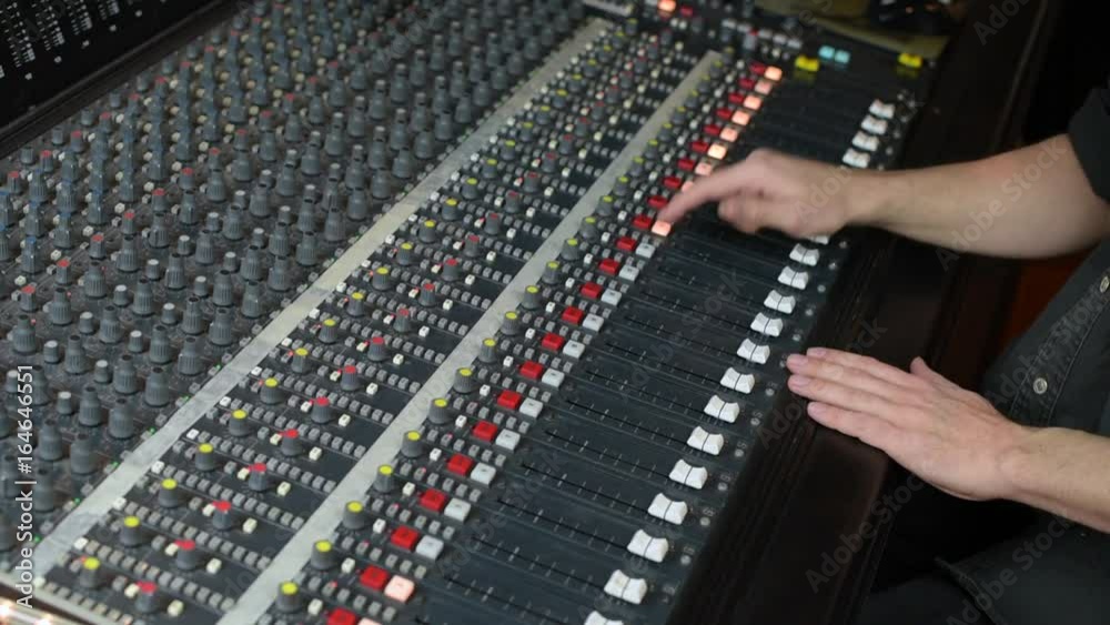 Hands moving faders on audio mixing desk Hands moving faders on audio mixing desk