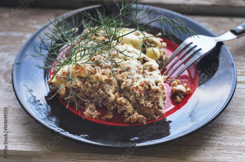 Foto Buckwheat porridge with cheese eggs on a red black plate