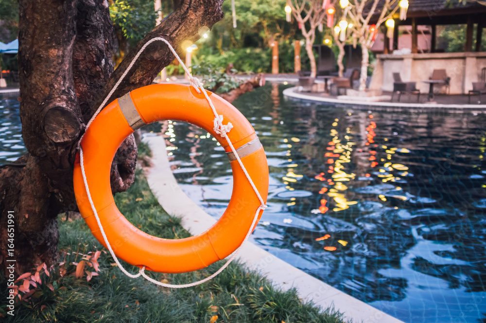 Life buoy or rescue buoy floating near pool to rescue people from drowning man. Safety equipment.