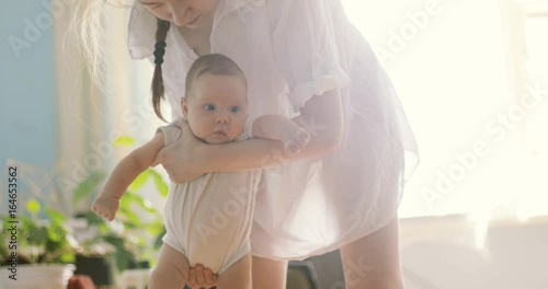 Mother holding baby boy sunny gentle bliss amused interested expression surprised nurse cheeks big eyes watching tender hands moving activity lulling lull dundle rocking child calm charming cute nanny photo