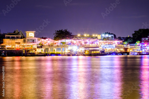 Bangkok, Thailand - JULY 17, 2017: Tha maharaj shopping mall and restaurant at night nearby the Grand Palace on the Chao Phraya River. Local boat at the pier, Bangkok, Thailand. photo