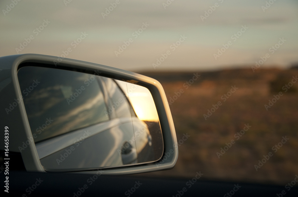 Review mirror during a road trip at sunset