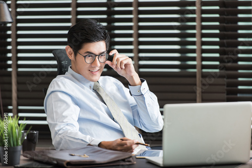 Asian businessman using his smartphone,computer in his office