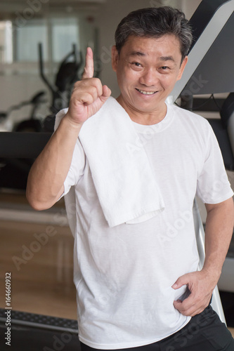 healthy, happy senior man working out in gym, giving no.1 finger gesture, winning or success concept