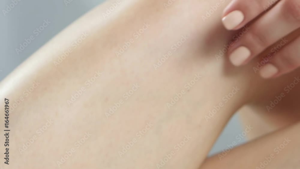 Girl spends her hand over her smooth skin on her leg. Close up