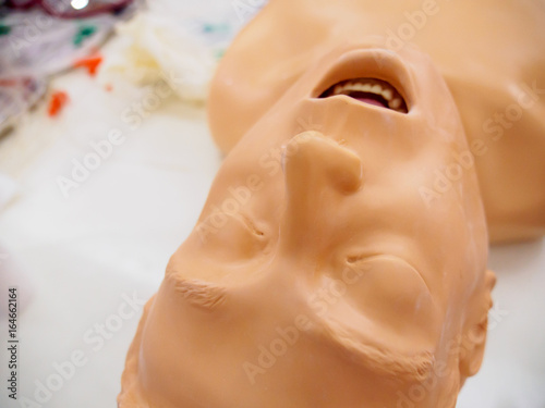 Close-up wide angle detail of the face of an unconscious, upside-down, medical mannequin used for training in cardiopulmonary resuscitation (CPR). Healthcare and education concept.