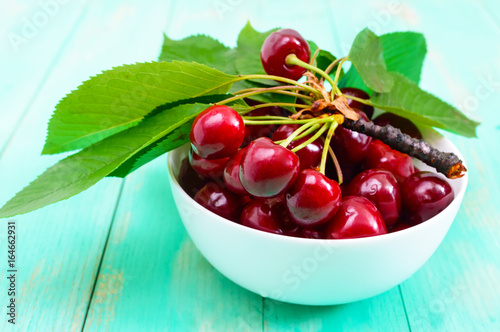 Ripe juicy red cherries in a ceramic bowl on a bright wooden background