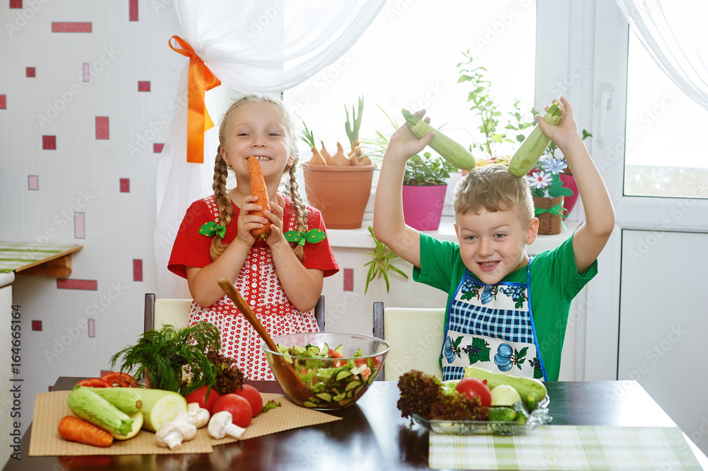 Children prepare salad vegetables . Happy kids in the kitchen . The concept of a healthy wholesome food Children prepare salad vegetables . Happy kids in the kitchen . The concept of a healthy wholesome food