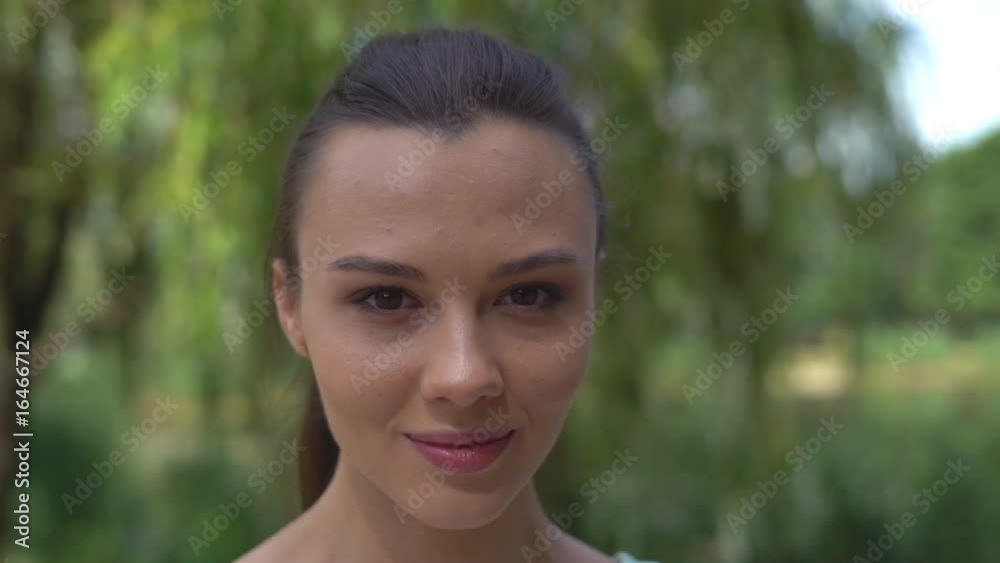 Caucasian woman looking through the window with a smile. Young attractive mixed-race girl smiling and piercing brown eyes. Sports woman fitness trainer is preparing to start training in a calm Caucasian woman looking through the window with a smile. Young attractive mixed-race girl smiling and piercing brown eyes. Sports woman fitness trainer is preparing to start training in a calm