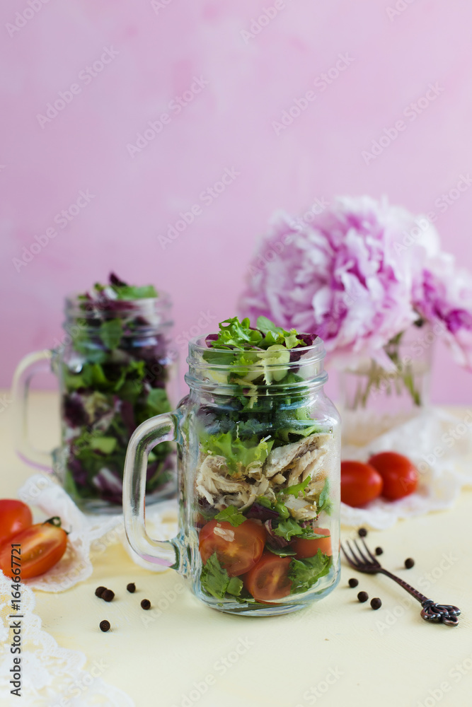 Chicken salad, greens and tomatoes on a pink background