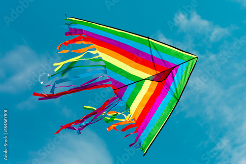 Multi-colored kite against a blue sky with clouds - freedom concept