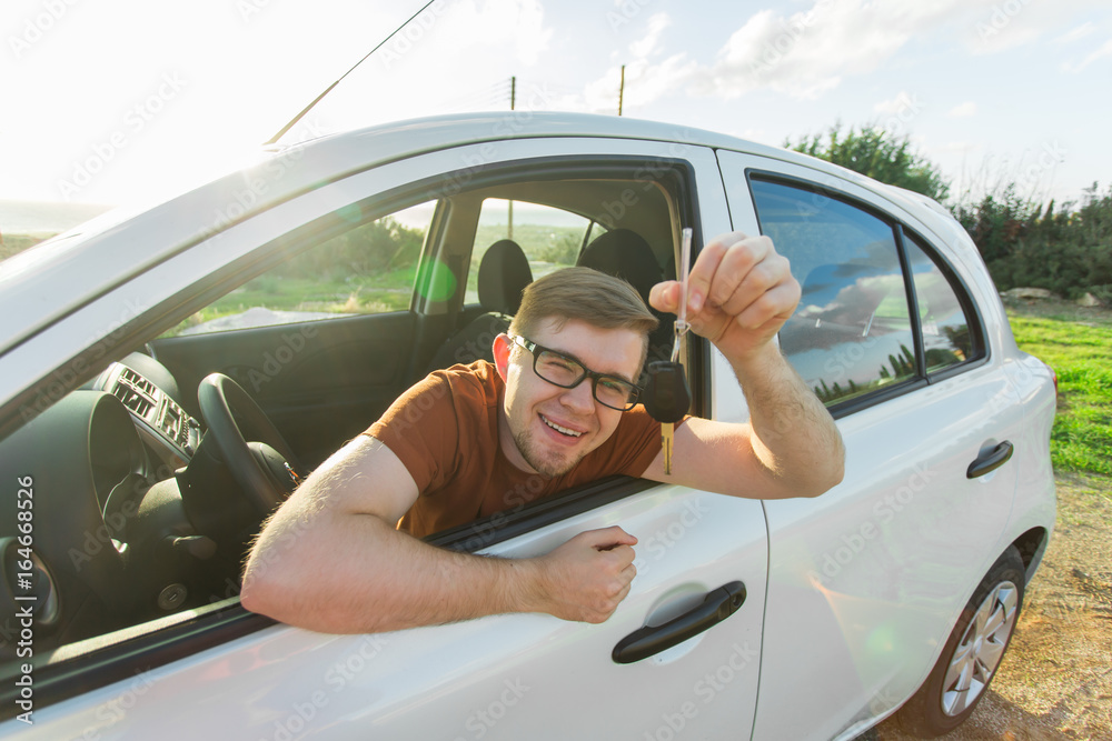 Naklejka premium Excited young man showing a car key inside his new vehicle