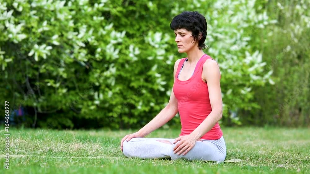 Girl is meditating. Professional yoga practicing in park doing breathing exercises Girl is meditating. Professional yoga practicing in park doing breathing exercises