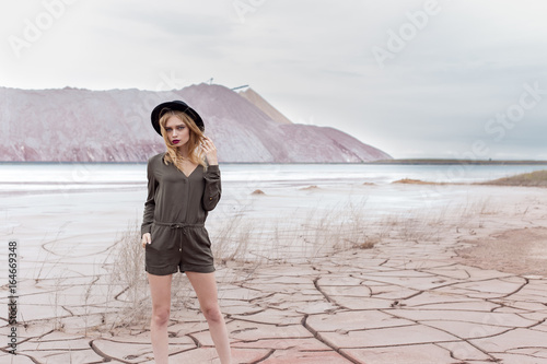 Beautiful sexy slender girl in a black hat in the mountains with a strong wind