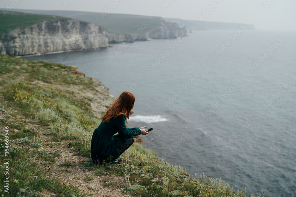 Beautiful young woman on a cliff of a mountain near the sea Beautiful young woman on a cliff of a mountain near the sea