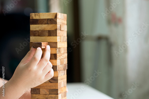 Close up hand kid take one block on a tower from a wooden block.