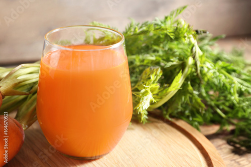 Glass of fresh carrot juice on wooden board