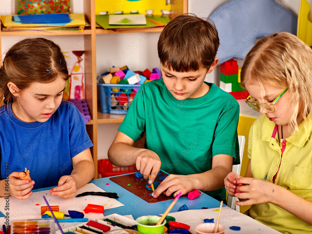 Fototapeta premium Mali uczniowie malujący w klasie szkoły artystycznej. Chłopiec i dziewczynka dzieci rysowanie farbami na stole. Portret dzieci w przedszkolu. Dzieci uczą się być przyjaciółmi w zespole.