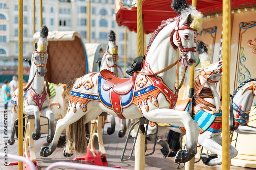 Horses on a carnival Merry Go Round. Old French carousel in a holiday park. Big roundabout at fair in amusement park.