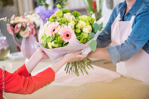cropped shot of florist giving beautiful flower bouquet to client