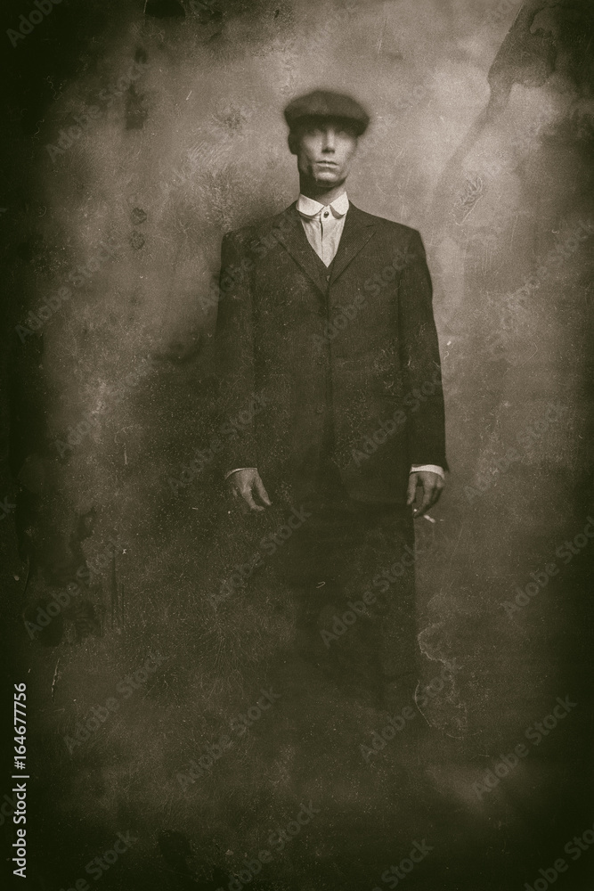 Obraz premium Antique wet plate photo of 1920s english gangster standing with cigarette. Wearing suit and flat cap.