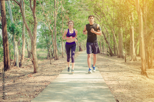two young people running together on road. Man and woman jogging outdoors. © Panumas