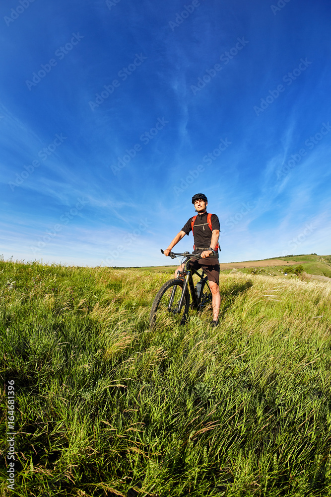 Young cyclist riding mountain bicyclist against beautiful sunset in the countryside. Young cyclist riding mountain bicyclist against beautiful sunset in the countryside.