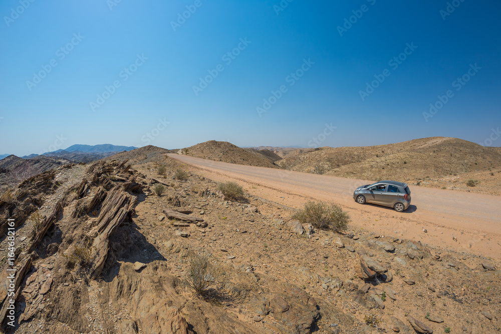 Car on gravel road in the Namib desert, Namib Naukluft National Park, main travel destination in Namibia, Africa. Concept of people traveling and adventures.
