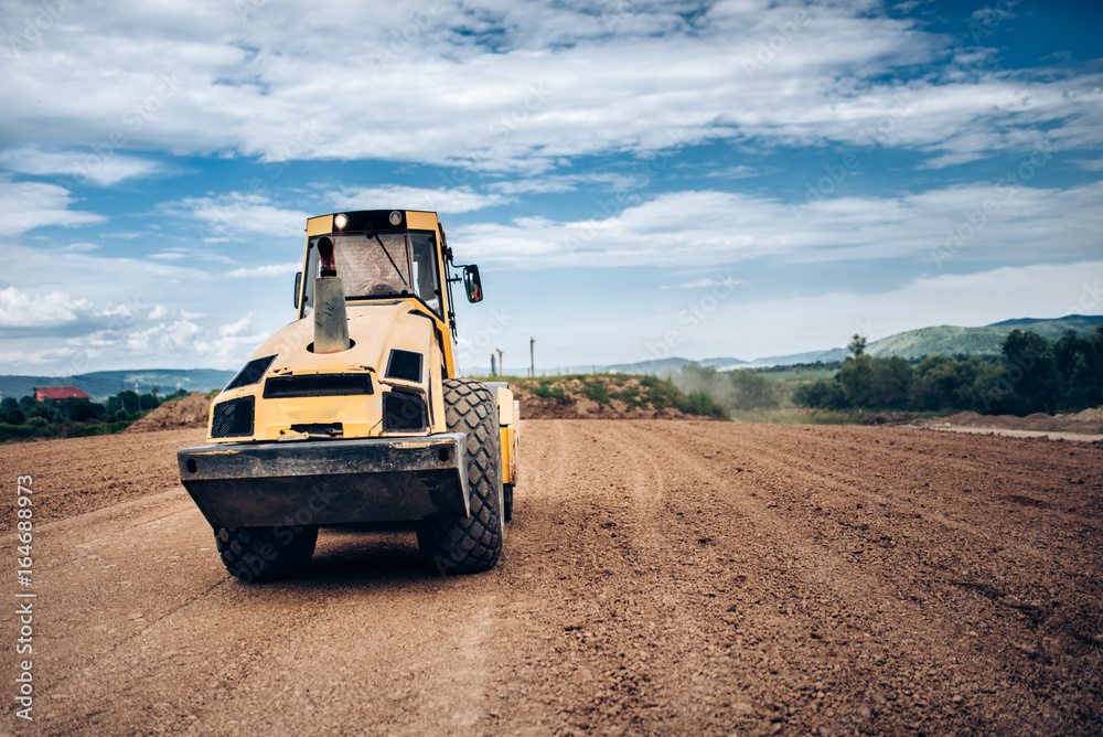 Obraz premium Vibratory Soil Compactor during highway building. Industrial roadworks with heavy-duty machinery