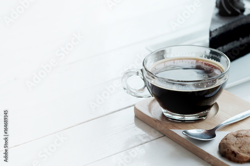 hot americano black coffee and A piece of charcoal cake on white wooden table. Have some space foe write wording