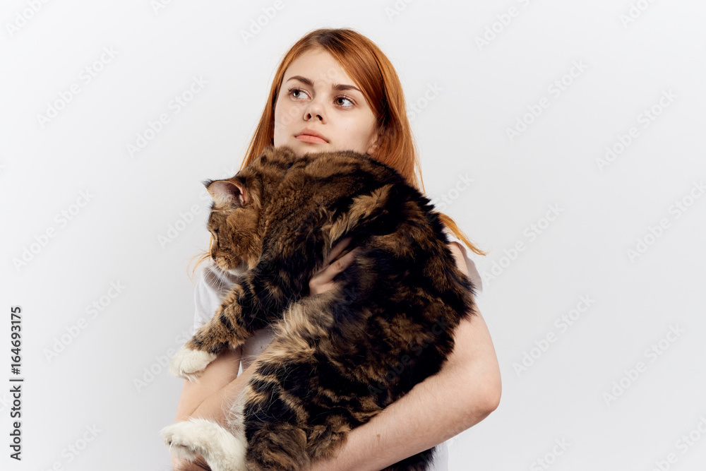 Young beautiful woman on a light background holds a cat