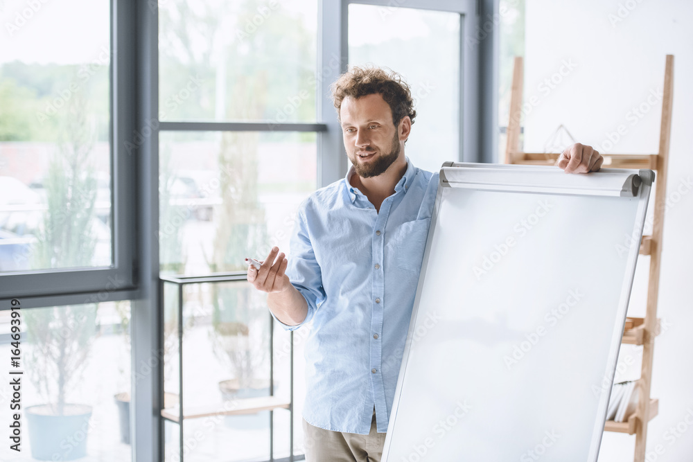 young businessman making presentation at white board in office