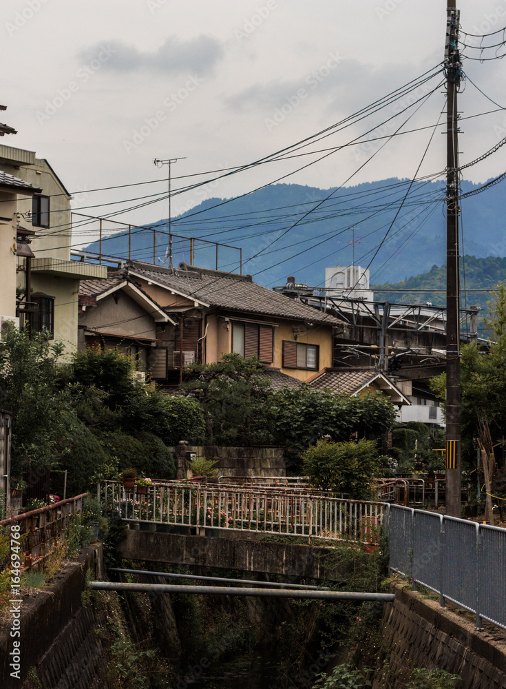 Beautiful scene in a small town in Japan near Kyoto of a river, Japanese houses and blue mountain the background Beautiful scene in a small town in Japan near Kyoto of a river, Japanese houses and blue mountain the background