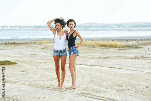 two girls model posing lying on the sand . The concept of summer clothes
