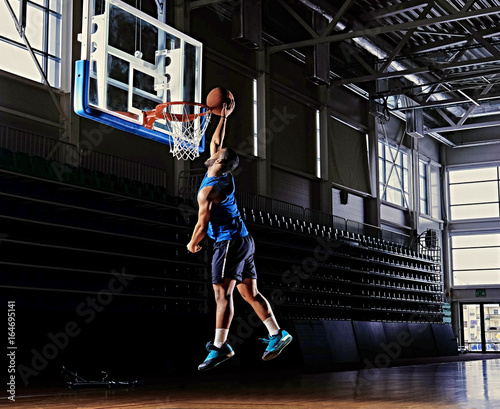 Black professional basketball player in action on a basketball field. © Fxquadro