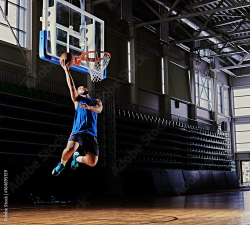 Black professional basketball player in action on a basketball field. © Fxquadro