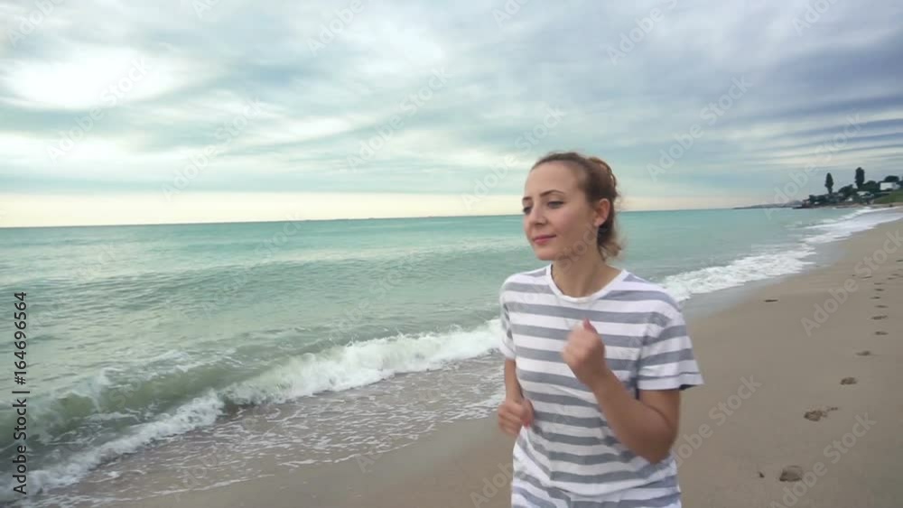 Athletic young woman running on the beach in slow motion Athletic young woman running on the beach in slow motion