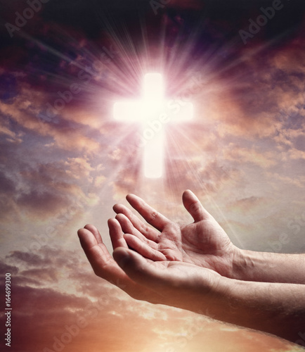Foto Hands reaching out with crucifix cross in sunset sky